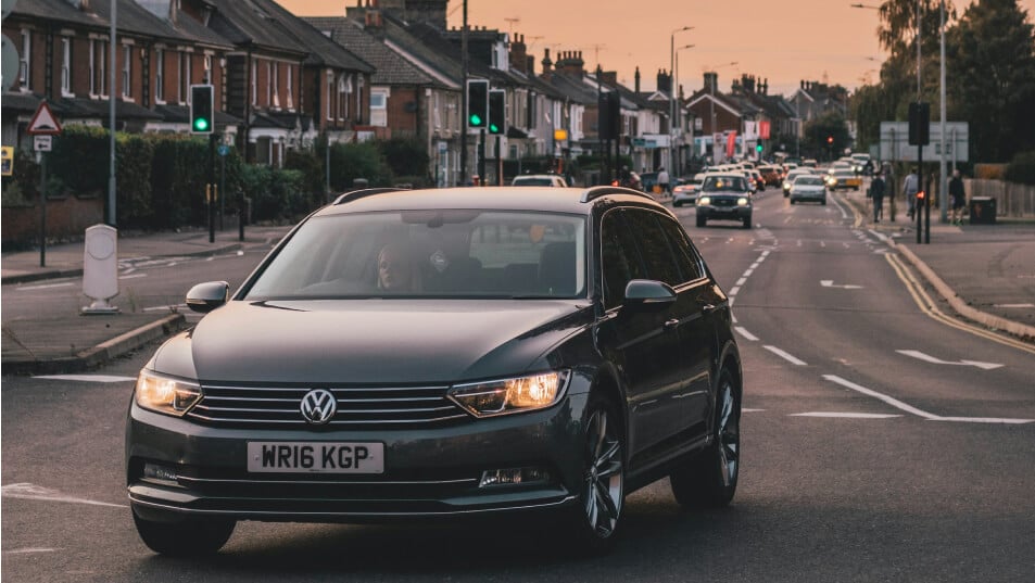 A car driving down a UK high street at dusk amid traffic